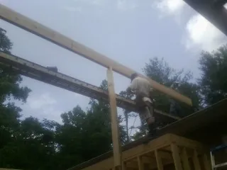 Carpenter setting a ridge beam over a new addition frame — Ice Dam Removal by Roofing Brothers in Lena