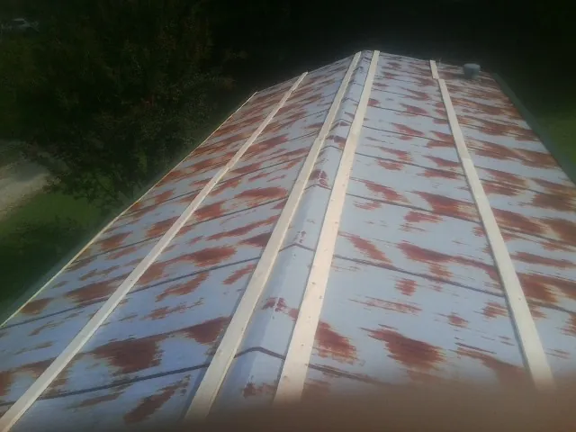 Rusted metal roof panels with new wood purlins before replacement — Storm Damage Roof Repair in Lena by Roofing Brothers