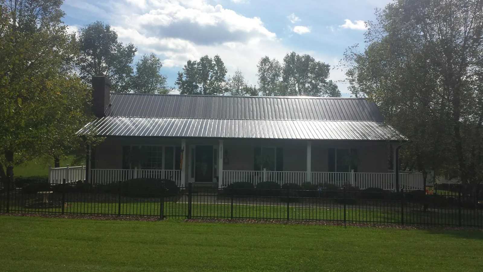 Gray metal roof on a brick ranch with a full width front porch — Gutter Guard Installation work by our crew in Lena