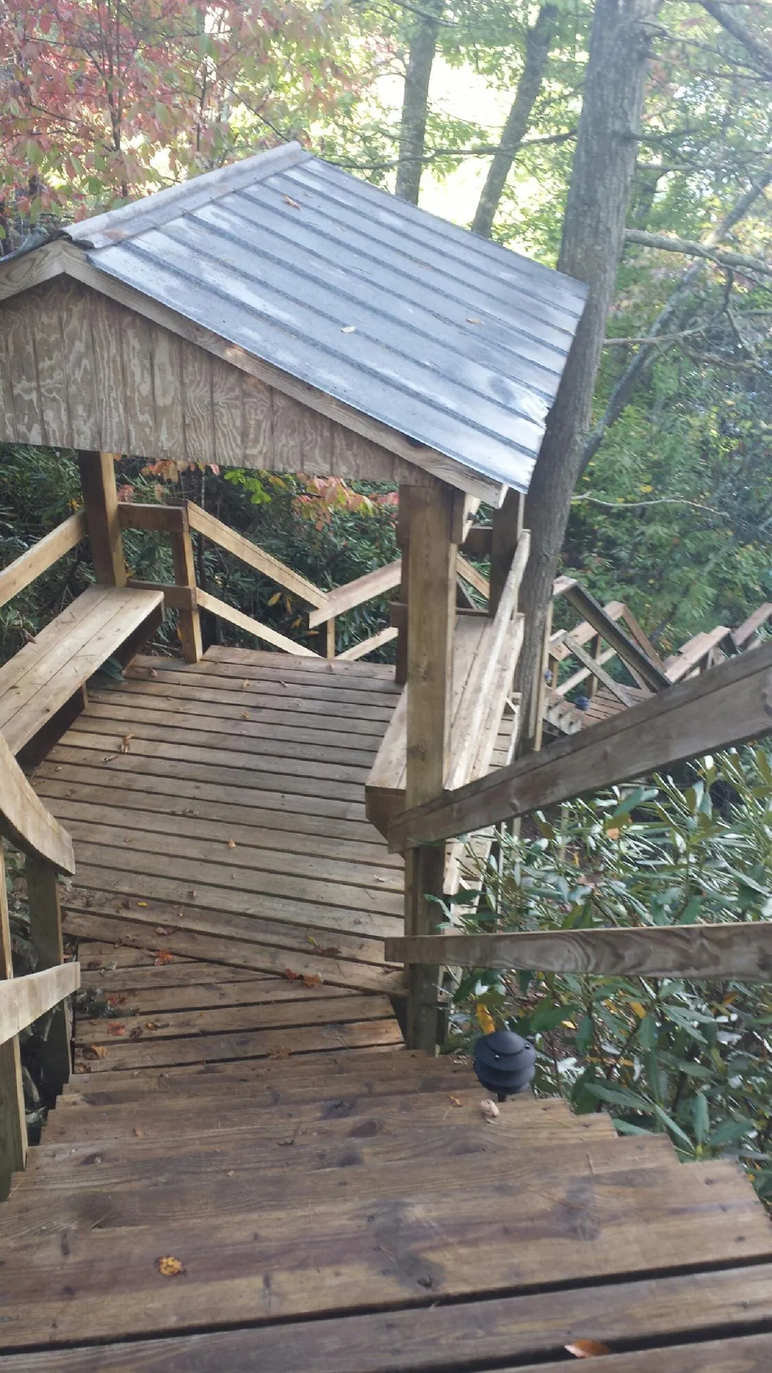 Metal roofed shelter over wooden steps on a wooded walkway — Skylight Repair & Installation work by our crew in Lena