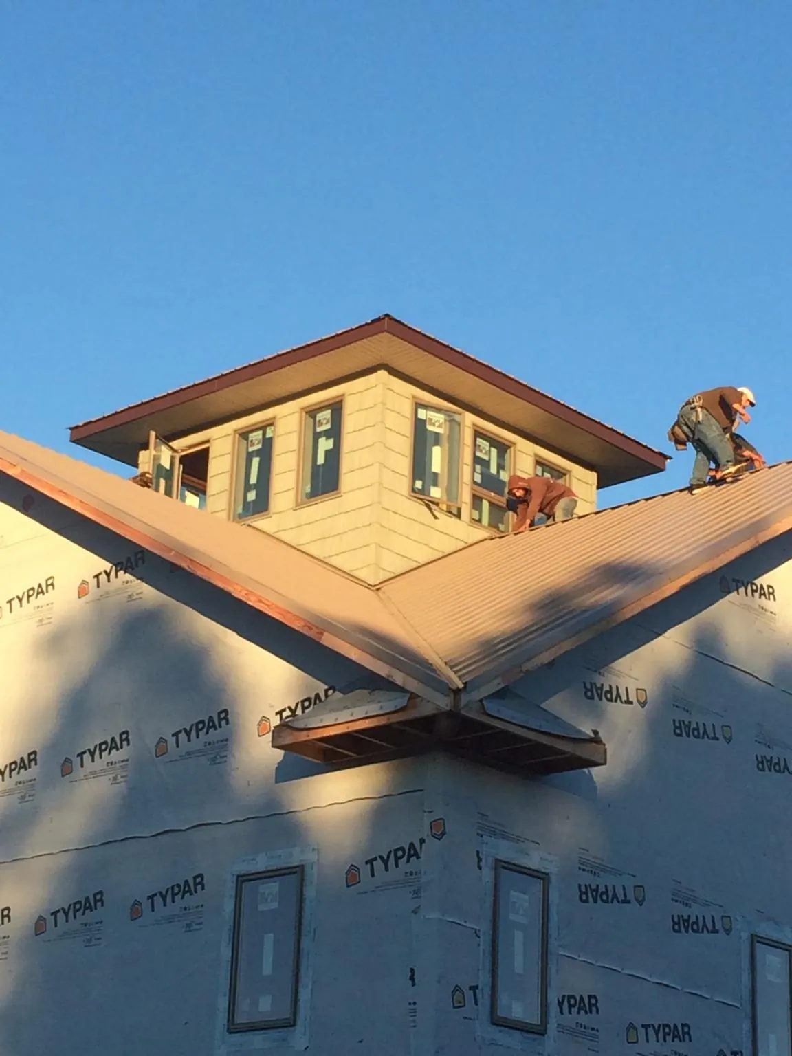 Roofers working around a rooftop cupola on a new metal roof at sunset — Roof Waterproofing in Lena by Roofing Brothers